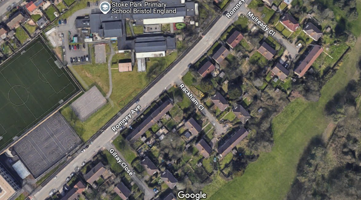 The site seen from above. The plot sits on the western side of Rackham Close in Bristol, surrounded by two storey terraces and semi-detached pairs, with Stoke Park Primary School directly across Romney Avenue. The same pattern of empty plots repeats at the mouth of each close running off Romney Avenue.
